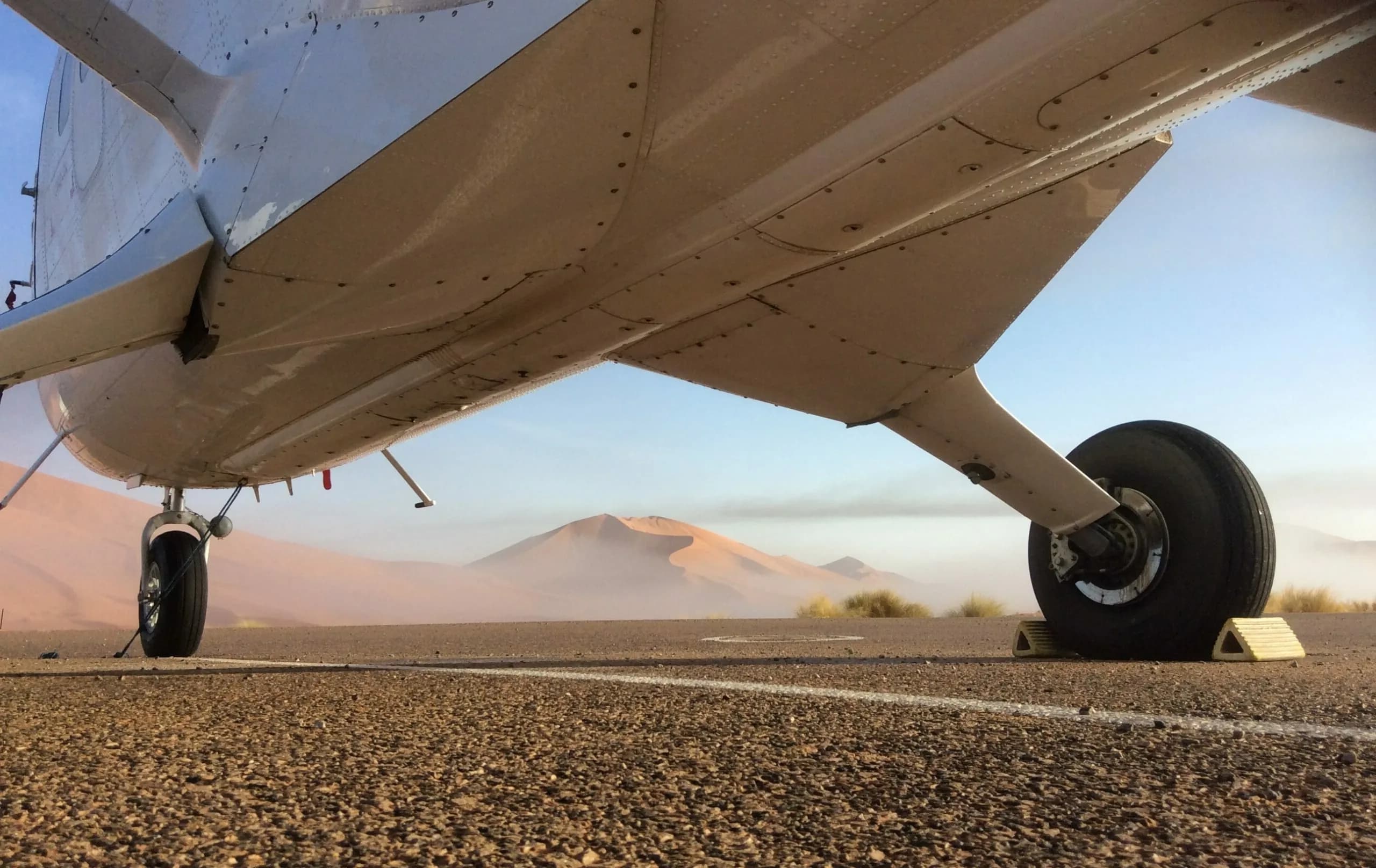 Golden desert dunes seen from the cabin of a Twin Otter, under the wing.