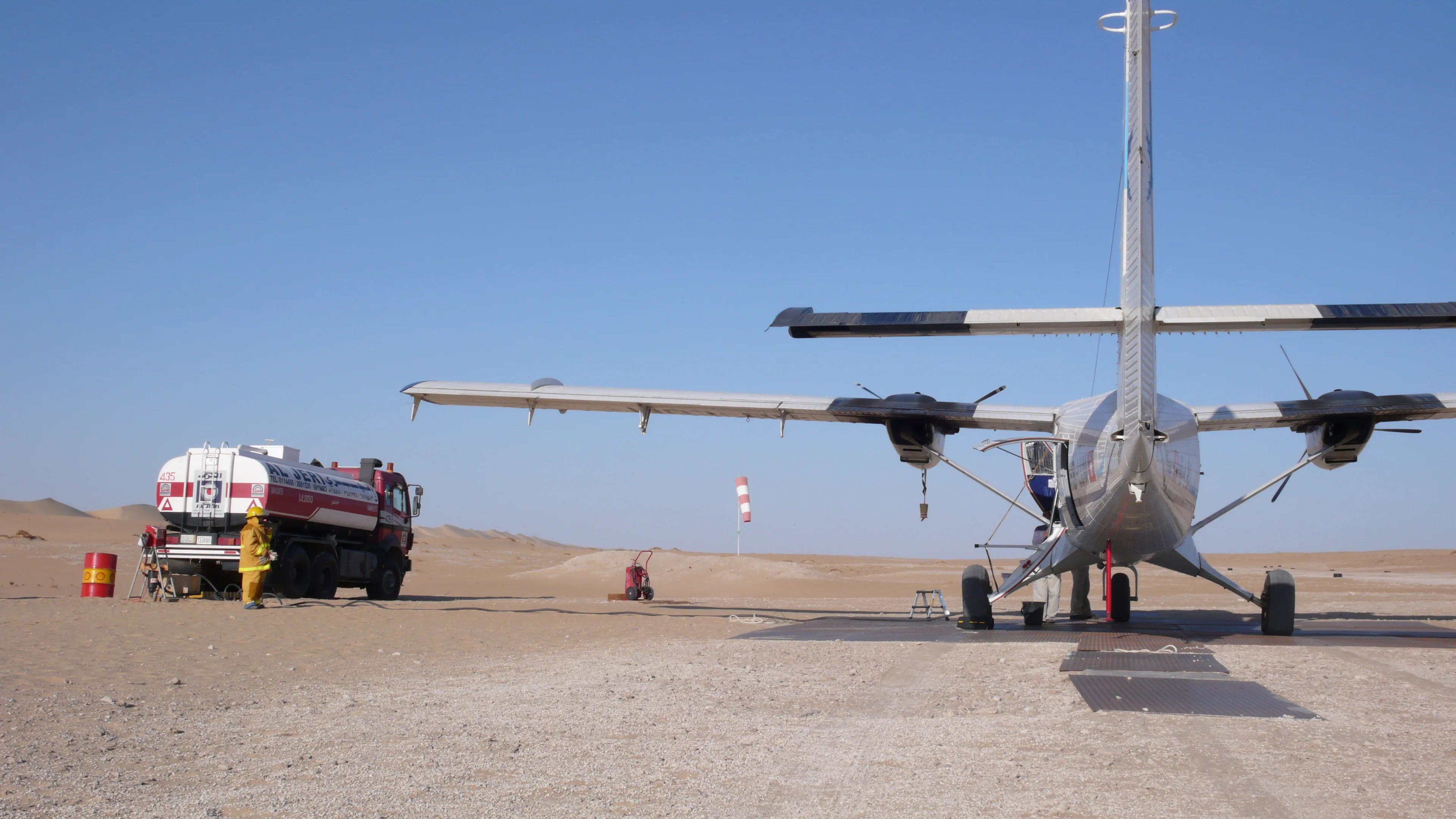 A Zimex Twin Otter being refuelled on a desert strip, seen from behind