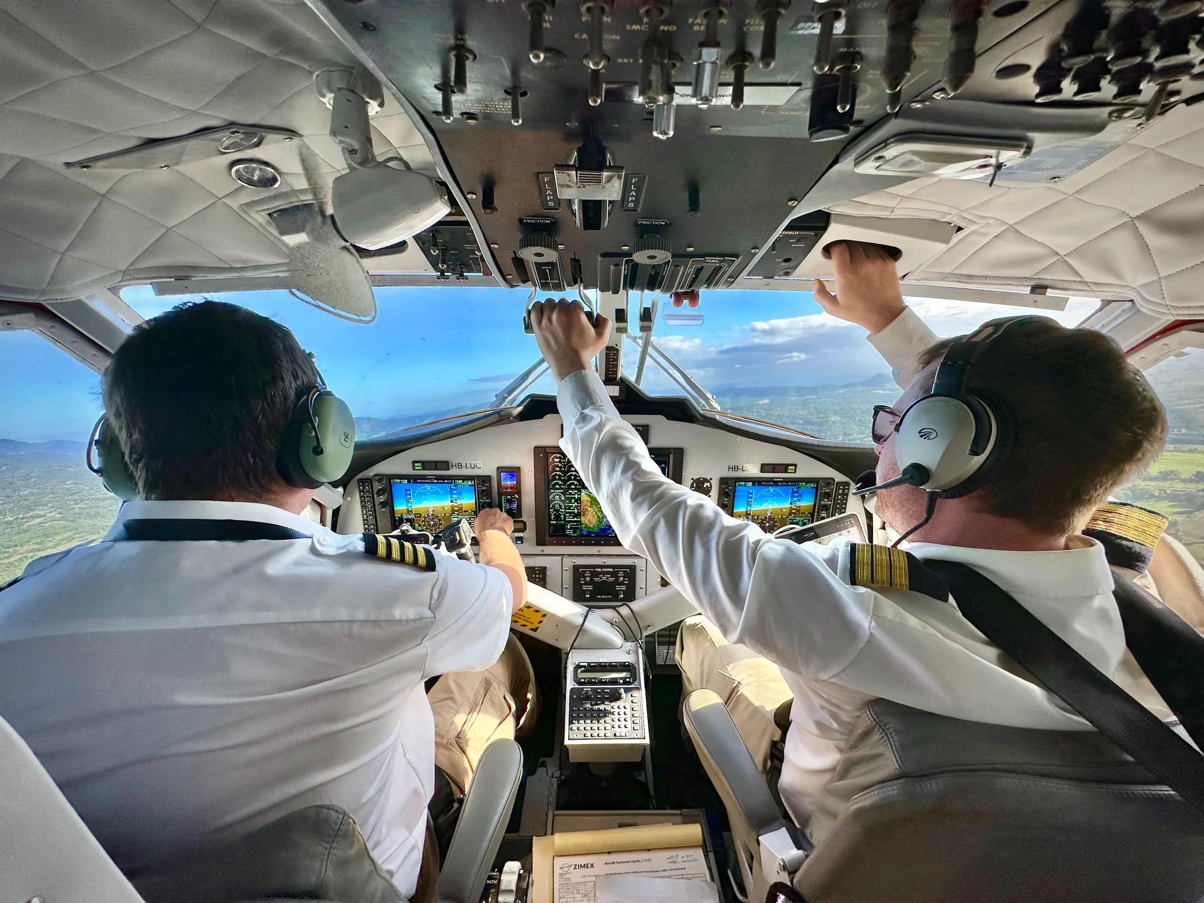 Two Zimex pilots in the cockpit of a Twin Otter in flight, seen from behind
