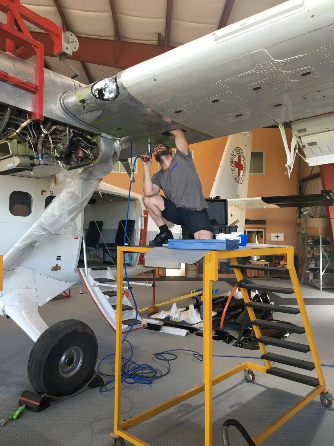 Engineer working on the wing and engine of an ICRC Twin Otter in the hangar