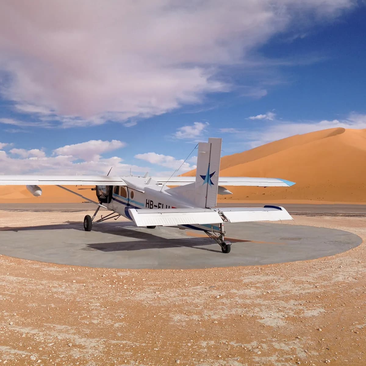 A Pilatus Porter on a sand strip between dunes.