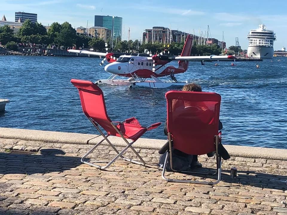 A Nordic Seaplanes float Twin Otter moored on a harbour front, with two red deckchairs.